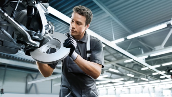 Mechaniker in Werkstatt montiert Bremsscheibe an Auto.