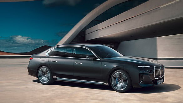 Dunkler BMW 7er vor moderner Architektur, blauer Himmel im Hintergrund.