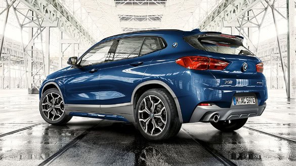Blauer BMW X2 in heller Halle, Seitenansicht, zeigt Fahrzeugdetails und stilvolles Design.