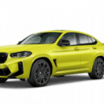 Gelber BMW X4 M vor schwarzem Hintergrund, seitliche Frontansicht.