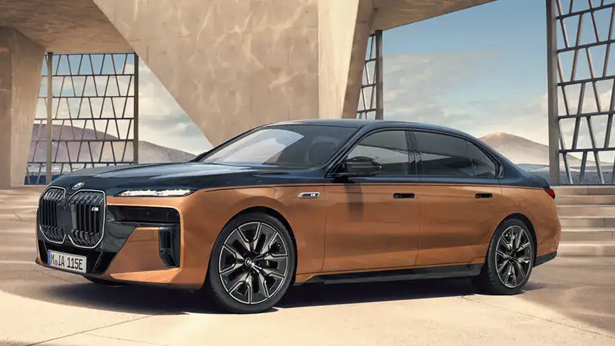 BMW i7 M70 in Zweifarblackierung steht vor moderner Architektur, sonniger Himmel im Hintergrund.