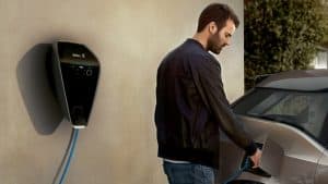 Mann lädt ein Elektroauto an einer BMW-Wandladestation.