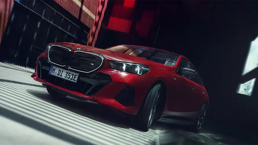 Roter BMW i5 M60 in einem dunklen Raum, seitlich von vorne fotografiert.