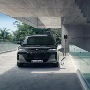 Schwarzer BMW vor moderner Garage, angeschlossen an eine Ladestation, umgeben von Glas und Beton.