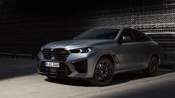 Silberner BMW X6 M parkt auf hellem Beton vor dunkler Wand bei BMW Autohaus Mülheim.